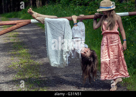 6- filles de 7 ans dans une robe d'été, les filles jouent sur une route forestière, barrière en bois Banque D'Images