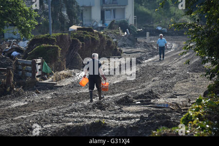 La Bavière, Allemagne. 06 Juin, 2016. Un homme transportant des seaux promenades le long d'une rue ravagé par les inondations dans la région de Simbach am Inn, Allemagne, 06 juin 2016. Sept personnes sont mortes dans la ville à la suite des inondations qui ont également causé des dommages considérables. Dpa : Crédit photo alliance/Alamy Live News Banque D'Images