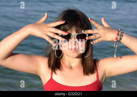 Fille, 12, portant des lunettes et montrant ses ongles peints aux couleurs vives Banque D'Images