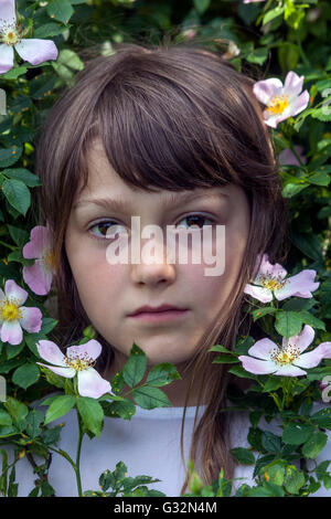 Fille de 7 ans en portrait d'enfant en fleurs de rose sauvages Banque D'Images