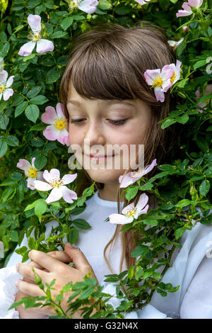 Fille de 7 ans enfant dans les roses sauvages fleurissant fleurs visage d'enfant Banque D'Images