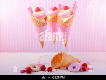 L'été est ici la vanille à thème des glaces en cônes gaufrette avec candy rose décorations sur une table en bois blanc contre une bande rose Banque D'Images