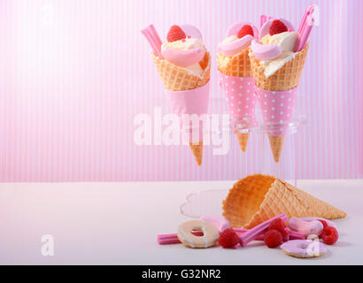 L'été est ici la vanille à thème des glaces en cônes gaufrette avec candy rose décorations sur une table en bois blanc contre une bande rose Banque D'Images