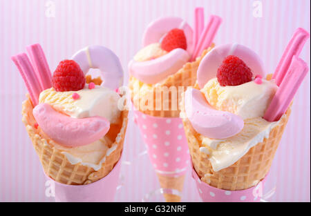 L'été est ici la vanille à thème des glaces en cônes gaufrette avec candy rose décorations sur fond de rayure rose. Banque D'Images