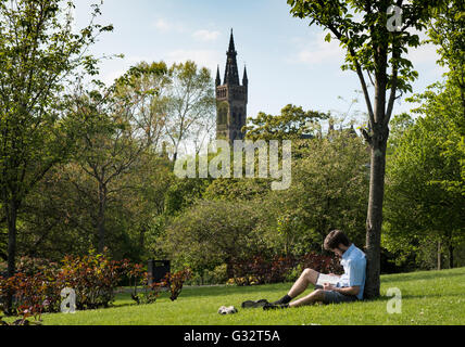 Student reading in parc Kelvingrove avec l'Université de Glasgow à l'arrière à Glasgow, Ecosse, Royaume-Uni Banque D'Images