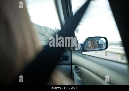 Reflet de woman in car wing mirror Banque D'Images