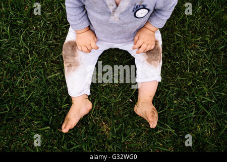 Vue de dessus de baby boy sitting on grass avec genoux sales Banque D'Images