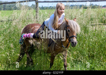 6- petite fille de 7 ans avec son poney, enfant à cheval, enfant sur Shetland Pony Banque D'Images