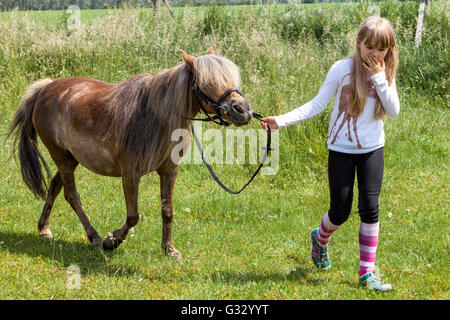 Petite fille poney, enfant de 6- 7 ans, la tête de poney par la bride Banque D'Images