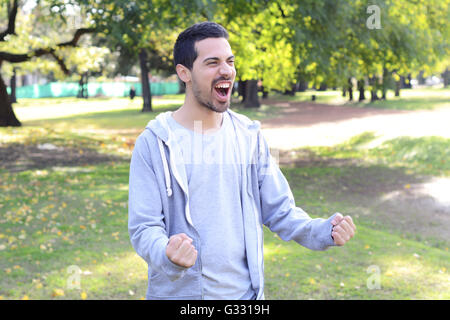 Portrait de jeune homme en faisant un geste de succès dans un parc. À l'extérieur. Banque D'Images