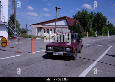 Une voiture quitter l'Dytyatky check point à l'entrée de la 30km large zone interdite autour de la centrale nucléaire de Tchernobyl en Ukraine le 04 juin 2016. L'accident de Tchernobyl a eu lieu le 26 avril 1986 à la centrale nucléaire de Tchernobyl, dans la ville de Pripyat et a été le pire accident nucléaire de l'histoire en termes de coûts et de pertes. Banque D'Images