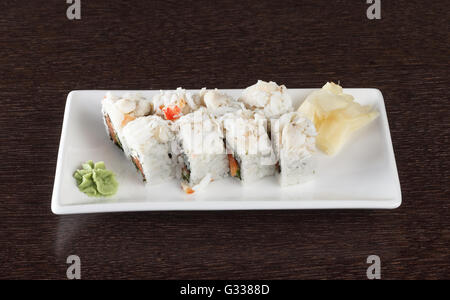 Rouleaux de Sushi sur une plaque avec du thon et du gingembre sur table en bois brun foncé. Vue de côté. Banque D'Images