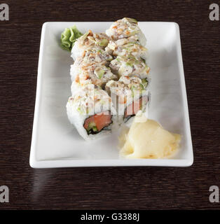 Rouleaux de Sushi sur une plaque avec du thon et du gingembre sur table en bois brun foncé. Vue de côté. Banque D'Images