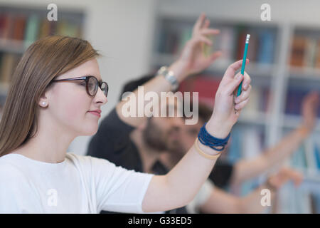 Groupe d'étudiants intelligents soulever Haut les mains à l'école classe de class Banque D'Images