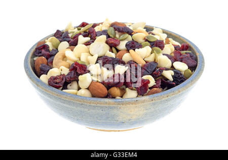Vue latérale d'un bol rempli d'un assortiment de noix et canneberges séchées, mélange montagnard isolé sur un fond blanc. Banque D'Images