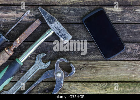 Téléphone à l'aide de réparation d'outils. ancien atelier avec de nouvelles technologies. l'arrière-plan pour le travail de menuiserie. Banque D'Images