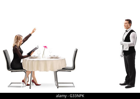 Femme blonde assise à une table de restaurant et appelant le garçon isolé sur fond blanc Banque D'Images