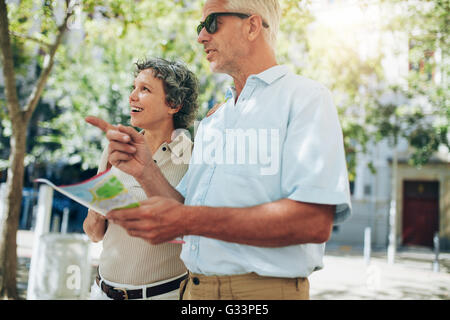 Couple d'heureux touristes la lecture d'une carte. Man pointing at a lieu avec une femme à admirer la vue. Banque D'Images