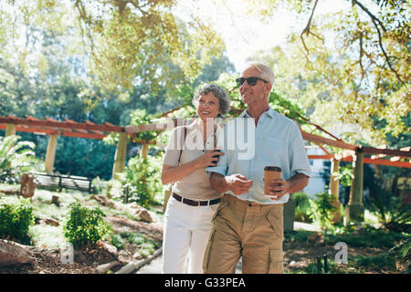 Tourné à l'extérieur de romantic couple bénéficiant d'une promenade dans le parc. L'homme et la femme mature en vacances, à la fois d'admirer une vie Banque D'Images