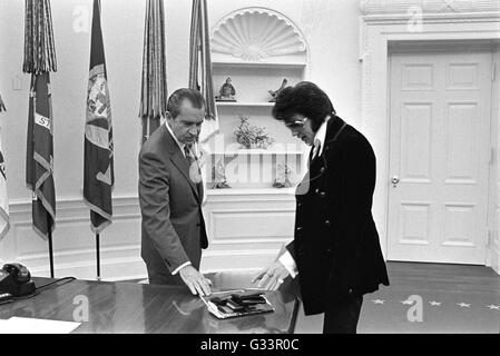 Elvis Presley présente une photographie autographiée de président américain Richard M. Nixon dans le bureau ovale à la Maison Blanche le 21 décembre 1970 à Washington, DC. La réunion a été ouverte par Presley, Nixon qui a écrit une lettre de six pages en vue d'une visite avec le président et en suggérant qu'il soit fait un 'agent fédéral-at-large' dans le bureau des narcotiques et des drogues dangereuses. Banque D'Images