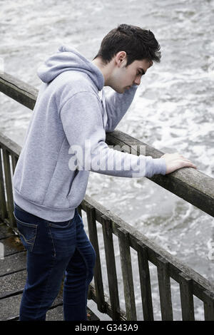 Jeune homme déprimé envisagent le suicide sur le pont sur la rivière Banque D'Images