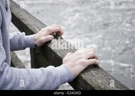 Jeune homme déprimé envisagent le suicide sur le pont sur la rivière Banque D'Images