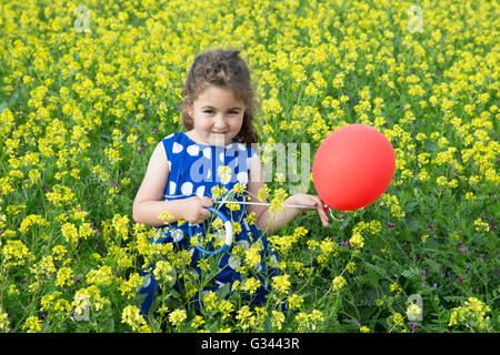 Tolède, Espagne, belle jeune fille jouant avec un ballon dans un champ de fleurs jaunes Banque D'Images