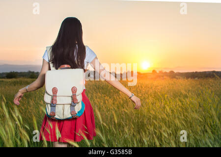 Jeune femme dans un champ de blé au coucher du soleil Banque D'Images