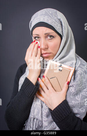 Femme musulmane gémissant sur une vieille photographie dans un cadre Banque D'Images