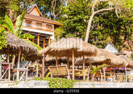 Un restaurant thaïlandais sur une plage tropicale avec des parasols de paille Banque D'Images