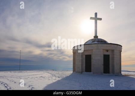 Cristian traverser une petite église avec soleil en contre-jour. Panorama d'hiver italien Banque D'Images