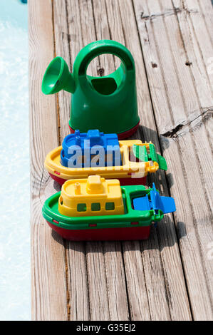 2 modèles de bateaux et d'un modèle arrosoir au bord d'un bassin pour enfants Banque D'Images