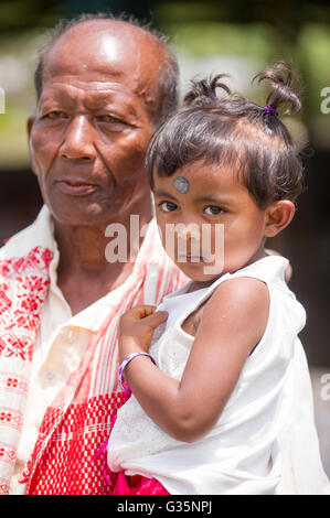 Une jeune fille est tenue par un parent dans le moule Bari Village dans le parc national de Kaziranga en Inde le 13 avril 2016. Credit : Banque D'Images