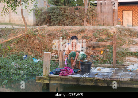 Femme laver les vêtements dans la rivière sur le lac Inle, Nyaung Shew, Birmanie, Myanmar, l'Asie du Sud, Asie Banque D'Images