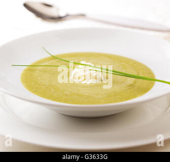 Assiette de soupe aux pois vert sain garnie de crème fouettée et d'herbes fraîches. Banque D'Images