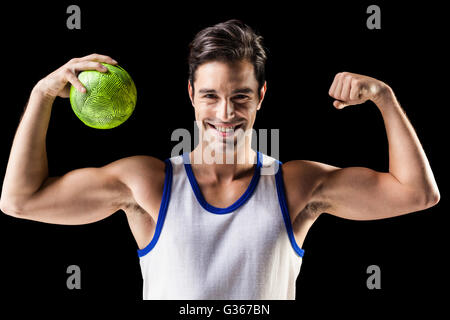 Portrait de l'athlète heureux man holding ball et montrant les muscles Banque D'Images