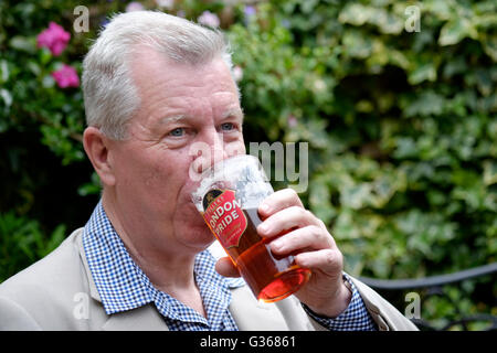 Un homme à la retraite bénéficiant d'une pinte de bière dans un pub et jardin england uk Banque D'Images