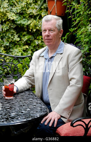 Un homme à la retraite bénéficiant d'une pinte de bière dans un pub et jardin england uk Banque D'Images