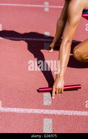 La mi-section de femme athlète prêt à commencer la course de relais Banque D'Images