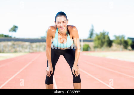 Athlète féminine fatigué debout sur une piste de course Banque D'Images