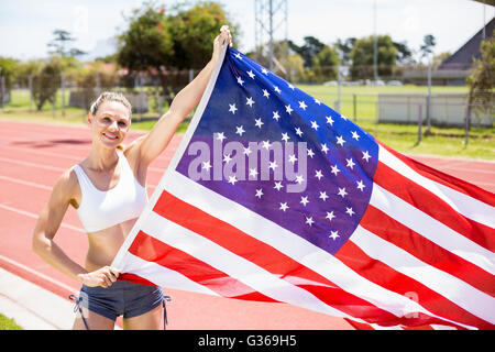 Portrait of happy female athlete holding up drapeau américain Banque D'Images