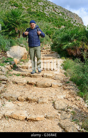 Les randonneurs sur un sentier de montagne passant shieling en pierre naturelle du Zingaro, Sicile Banque D'Images