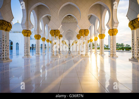 Une vue vers le bas une colonnade dans la Grande Mosquée de Sheikh Zayed à Abu Dhabi au coucher du soleil Banque D'Images