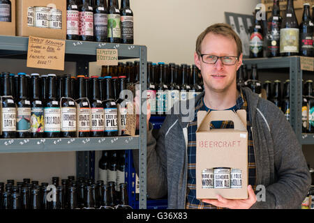 Le propriétaire d'Beercraft, spécialiste de la petite bière off-licence de Kelso, avec bières brassées localement tempête. Banque D'Images