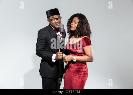 Couple Afro amerian singing into microphone vintage sur fond sombre Banque D'Images