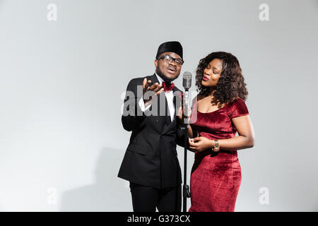 Beau couple afro amerian singing into microphone vintage sur fond sombre Banque D'Images