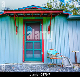 Un panneau métallique bleu turquoise et bâtiment avec garniture rouge avec l'avant-faux d'entrée et Rusty metal turquoise chaise vintage Banque D'Images