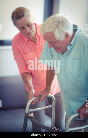 Senior woman aidant les homme à marcher avec walker Banque D'Images