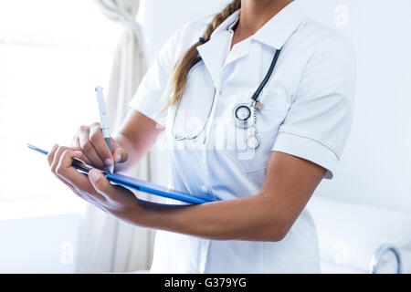 Female doctor writing on clipboard in hospital Banque D'Images