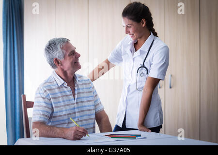 Aider un médecin senior man tout en appelant à l'élaboration d'adresses Banque D'Images